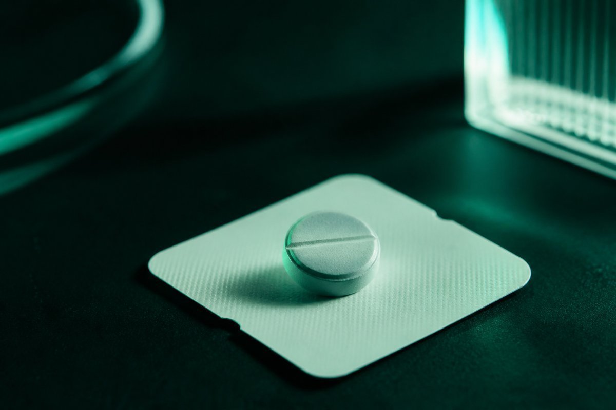 Forest-green still life: one 50 mg tablet on a lock card