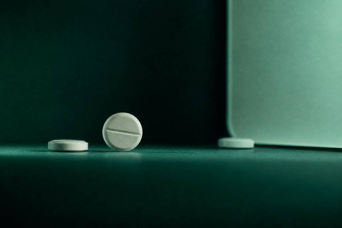 Forest-green still life: swollen caution, tablets paused