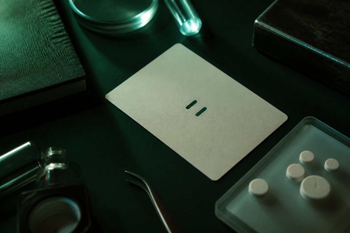 Forest-green still life: two small marks on a cycle card