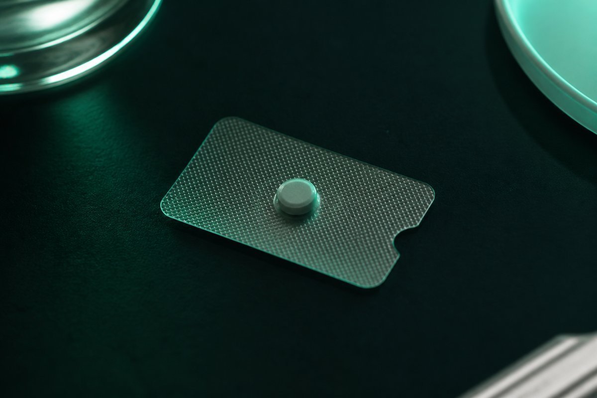 Forest-green still life: one tiny tablet on a lock card