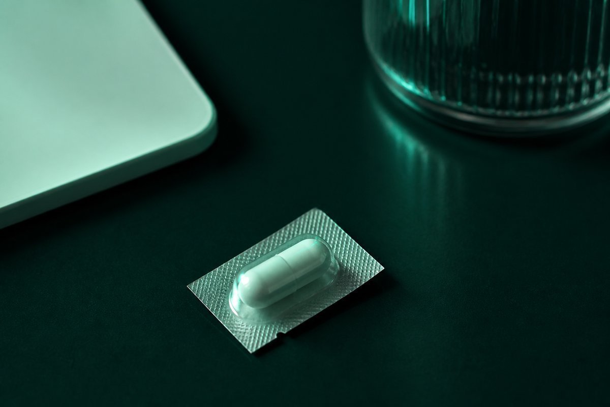 Forest-green still life: last sealed capsule in the strip