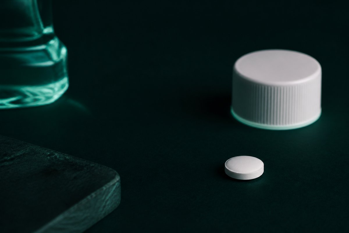 Forest-green still life: closed mouthwash cap, white tablet dry