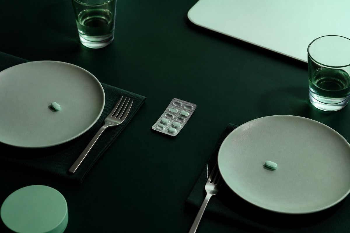 Forest-green still life: two place settings, one blister shared as a pair