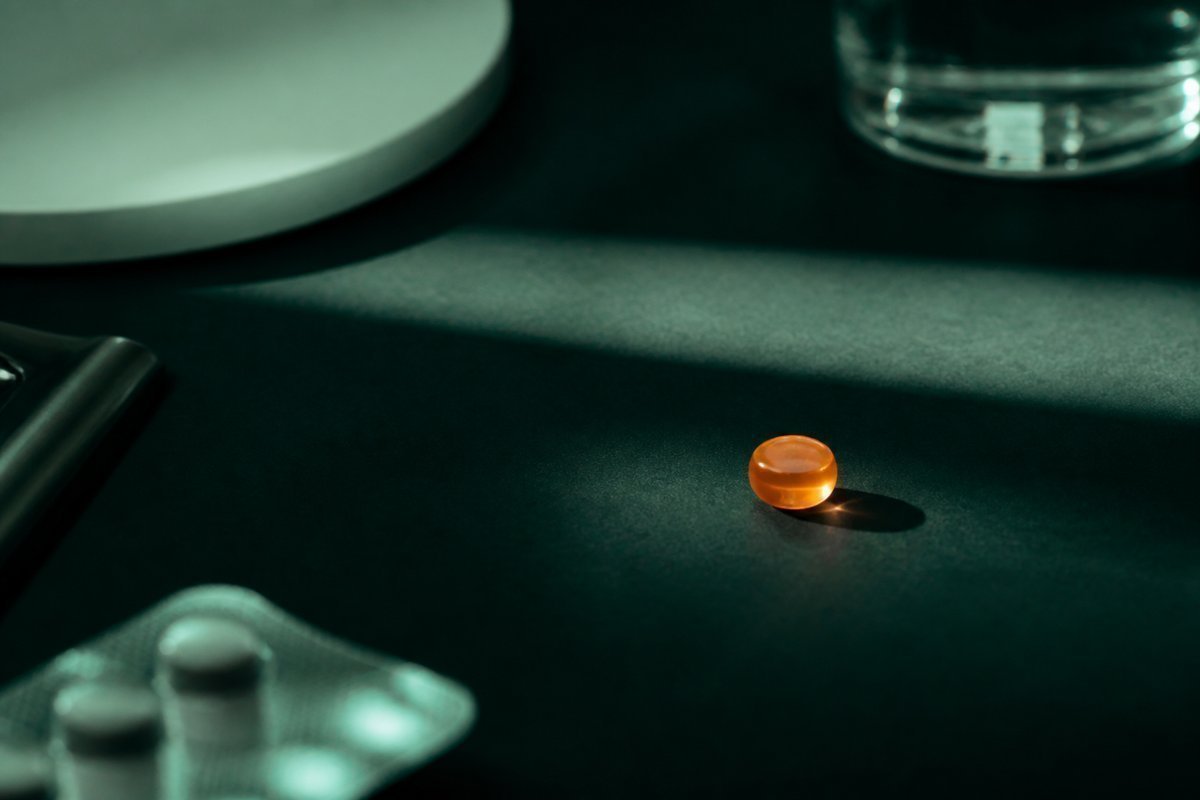 Forest-green still life: short four-hour window of light, amber tablet